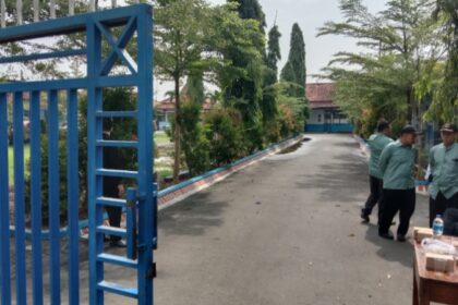 Para petugas keamanan berjaga di depan pintu pagar SMP Negeri 3 Comal, menghindar saat wartawan mengambil gambar